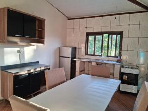 een keuken met een witte tafel en een koelkast bij Recanto verde in Ilhabela