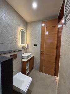a bathroom with a sink and a wooden door at Muskan Mount View Retreat, Mukteshwar in Mukteswar