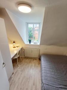 a bedroom with a bed and a desk and a window at Charming 1-bedroom Apartment A in Hjørring
