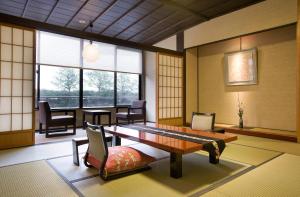 een kamer met een tafel, stoelen en ramen bij Kanazawa Chaya in Kanazawa