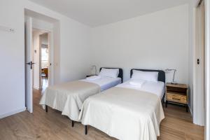 two beds in a room with white walls and wooden floors at Las casitas de mache - LAGOSSA in Cerler