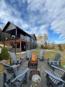 a group of chairs around a fire pit in front of a house at Vertigo - Fleuve & Montagnes in Les Éboulements