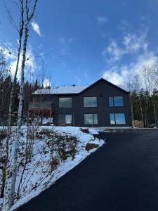 a large black house with snow in front of it at Vertigo - Fleuve & Montagnes in Les Éboulements