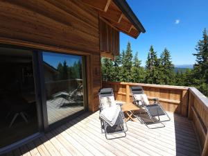 two chairs and a table on a wooden deck at The Lodges am Klippitztörl - Chalet in Klippitztorl