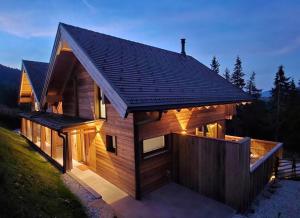 a wooden house with a lit up facade at The Lodges am Klippitztörl - Chalet in Klippitztorl +73 photos