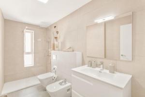 a white bathroom with a toilet and a sink at Oasis Penthouse Maspalomas in Maspalomas +12 photos