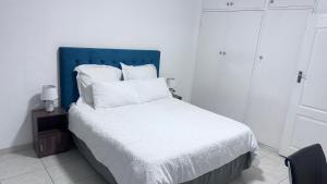 een wit bed met een blauw hoofdeinde en witte kussens bij Croydon Vista Luxe in Kempton Park