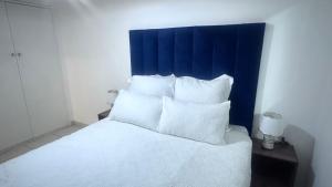 een wit bed met een blauw hoofdeinde en witte kussens bij Croydon Vista Luxe in Kempton Park