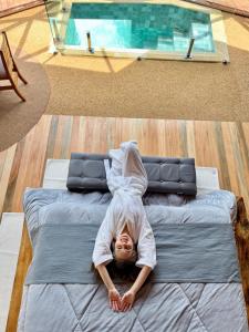 a child laying on a bed in front of a pool at Vila Rosa Lodges - Chalés e Domo in Praia Grande