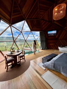 a woman walking through a room with a bed and a table at Vila Rosa Lodges - Chalés e Domo in Praia Grande
