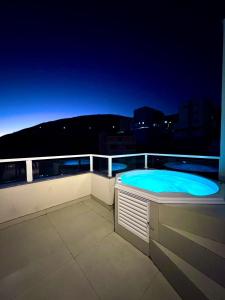 a swimming pool on the roof of a building at night at Charmoso Duplex com Jacuzzi in Poços de Caldas