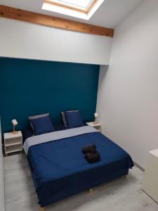 Charmant 3 pieces 2 chambres et parking في بونتولت-كومْبو: غرفة نوم بسرير أزرق ووسائد زرقاء