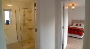 a bathroom with a shower and a bedroom with a bed at Ferry Lodge Cottage in Kilrush