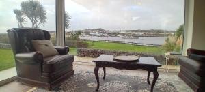 a living room with a chair and a table and a window at Ferry Lodge Cottage in Kilrush +23 photos