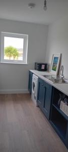 Ferry Lodge Cottage في غابات كيلرَش: مطبخ مع غسالة ملابس ونافذة +5 صور