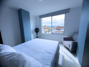 a bedroom with a bed and a window and a chair at Amplio Y Lujoso Apartasuite En El Centro in Cartago
