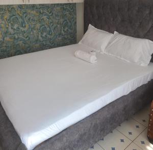 a large bed with white sheets and pillows on it at Avian suits in Kisumu
