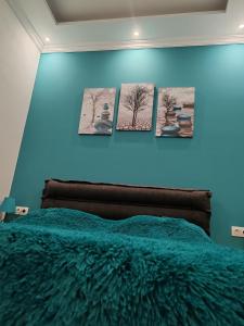 Un dormitorio azul con cuatro cuadros en la pared. en Linda, en Tiflis
