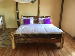 RubuguliにあるMigogo gorilla lodgeのベッドルーム1室(木製ベッド1台、紫色の枕付)