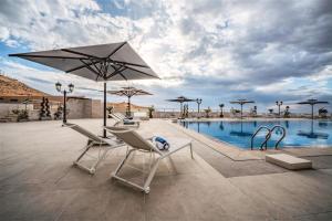a group of chairs and an umbrella next to a pool at Petra Pillars Luxury Hotel in Petra +60 photos