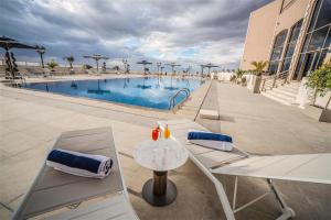 a pool with chairs and a table next to a building at Petra Pillars Luxury Hotel in Petra