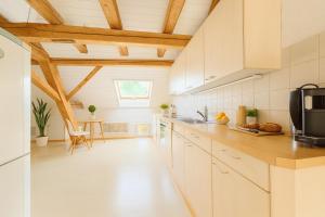 a kitchen with white cabinets and wooden ceilings at Aussergewöhnliche Loft Wohnung mit Hängenetzen und Schaukeln in Frauenfeld