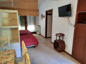een kleine kamer met een bed en een tv. bij La caracola in Villa Gesell