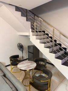 een woonkamer met een trap met stoelen en een tafel bij Next Level Apartments and Suites in Ibadan