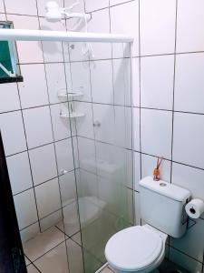 a bathroom with a toilet and a glass shower at Apartamento zimbros bombinhas in Bombinhas
