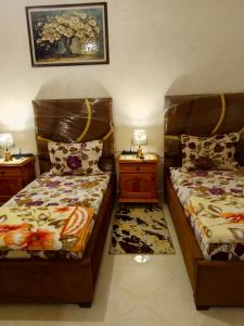 two beds in a room with two night stands and two lamps at Maison de vacances zuine in Oujda
