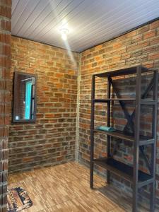 a room with a brick wall and a shelf at MOVE quartos de hotel in Pipa