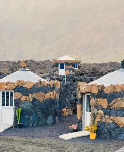 two buildings with white doors and a stone wall at Funco Du Santos in Portela