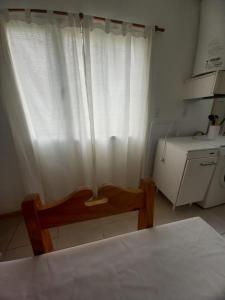 een kamer met een tafel, een stoel en een wit gordijn bij Viento Sur 2 in Estancia El Polomo