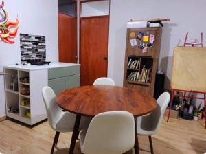 een eetkamer met een houten tafel en witte stoelen bij Casa hogareña Pequeña in Ica
