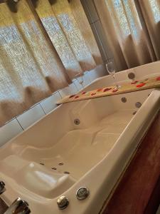 Quiosque Família Chalé Garça في جوانوبوليس: حوض استحمام مع كأسين من النبيذ فوقه +14 صورة