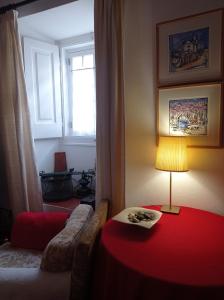 a living room with a red table and a lamp at Casa das Glicínias in Óbidos