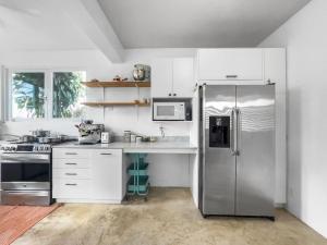 a kitchen with a stainless steel refrigerator and white cabinets at Marley n Enzos Surf Shack in Aguadilla