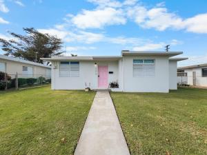 a white house with a pink door in a yard at Marley n Enzos Surf Shack in Aguadilla