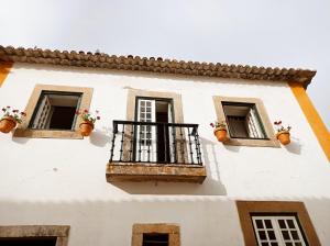 a white building with two windows and a balcony at Casa das Glicínias in Óbidos