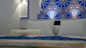 a bedroom with blue and white pillows and a bed at Dar Ouadie the pearl stay in Chefchaouen