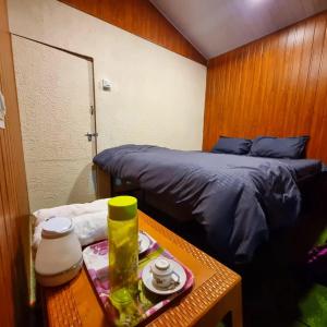 Pawan leke cottage في Kolvan: غرفة نوم صغيرة مع سرير وطاولة مع منضدة sidx