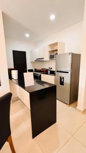 a kitchen with a black counter and a refrigerator at Departamento moderno con alberca ideal para una escapada cómoda in Playa del Carmen