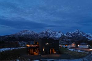 een huis met sneeuw bedekte bergen op de achtergrond bij Premium Rural Apartment - Leknes in Leknes
