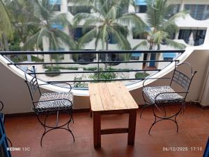een tafel en 2 stoelen op een balkon met palmbomen bij Appartement Saly plage in Saly Portudal