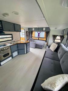 Una sala de estar de una casa rodante con un sofá y una cocina. en Clamping Caravan, en Whanganui