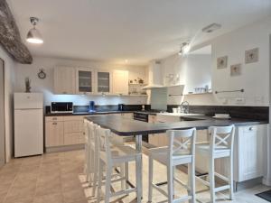 - une cuisine avec une grande île dotée d'appareils électroménagers blancs dans l'établissement La Charmésienne, à Charmé 3 autres photos