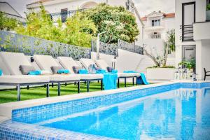 Villa Palace Al Nera في تروغير: حمام سباحة مع كراسي استرخاء وطاولة بجوار منزل +117 صورة