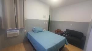 una piccola camera con letto blu e divano di Ap Umarizal a Belém