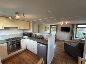 eine Küche mit weißen Schränken und ein Wohnzimmer in der Unterkunft Athelington Lodge - Chestnut in Horham