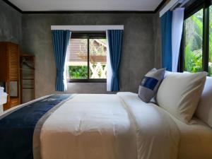 ein Schlafzimmer mit einem großen Bett mit blauen Vorhängen und einem Fenster in der Unterkunft Baan Ati Villas in Ban Han Pa To + 21 Fotos